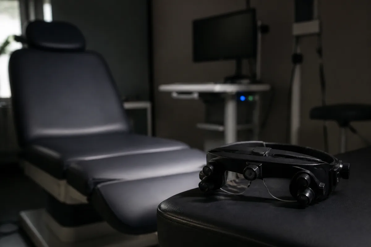Lunettes de vidéonystagmoscopie posées près d&rsquo;un fauteuil d&rsquo;examen dans une salle sombre